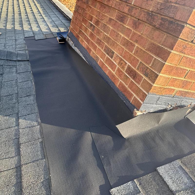 Custom chimney flashing installation on asphalt roof