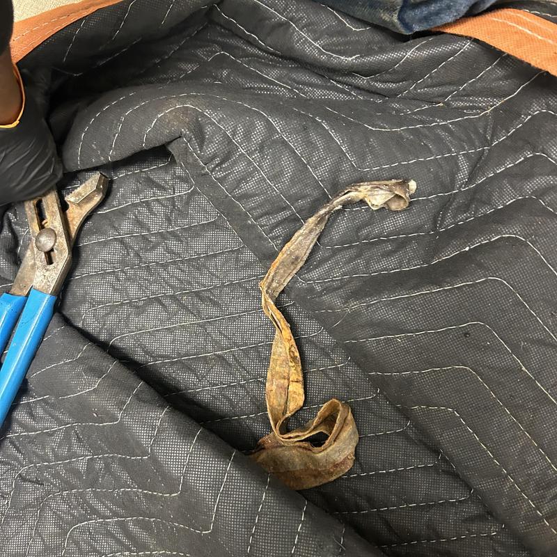 Main line clog debris with plumber tool on mat