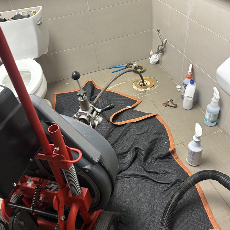 Main line sewer cleaning machine in commercial restroom