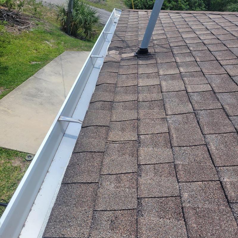 Roof shingles with soft spots and damage near gutter