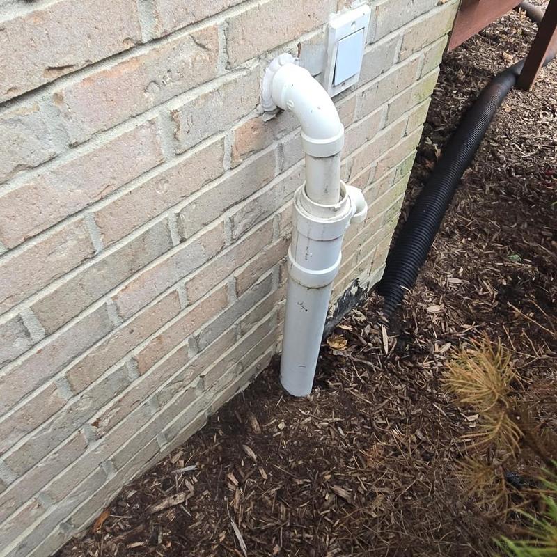 Sump pump discharge pipe outside brick house