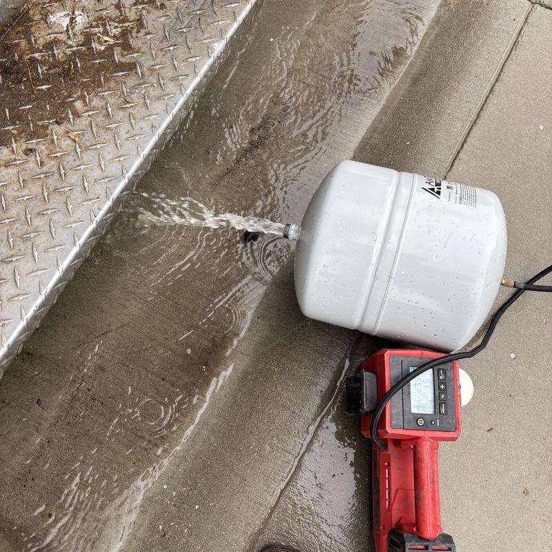 Expansion tank with leaking pipe spraying water on concrete