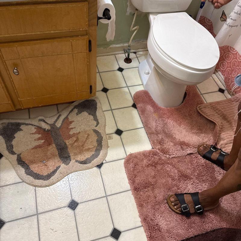 Toilet with floor mats in bathroom corner