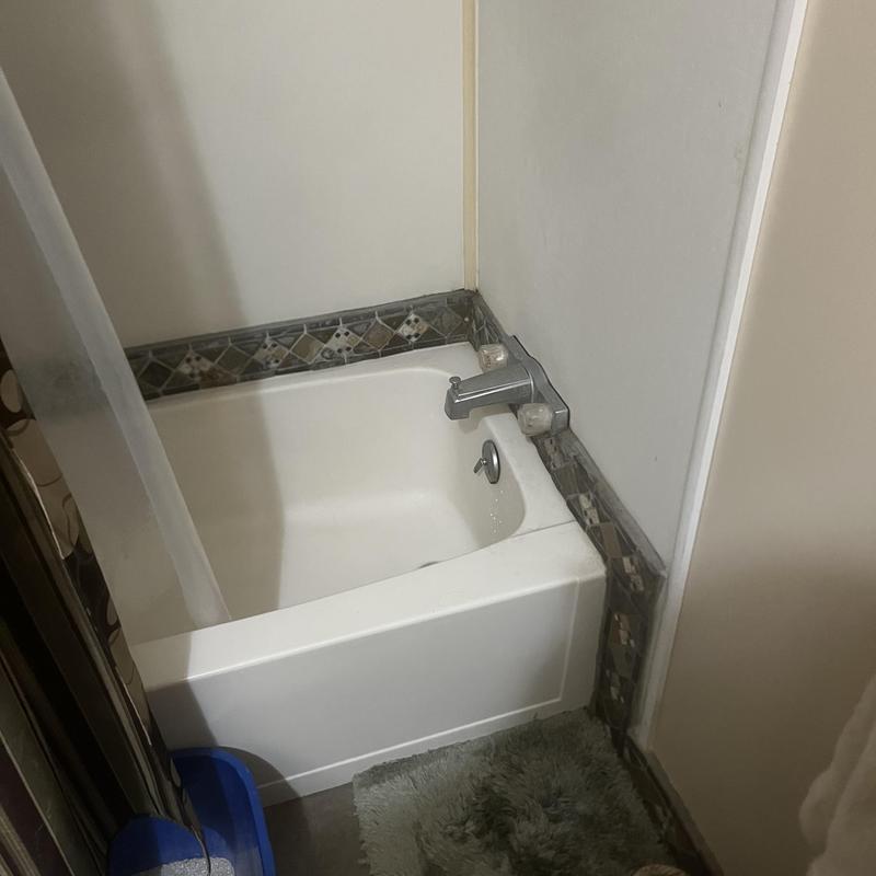 Bathtub trim sealed with clear silicone in hallway bath