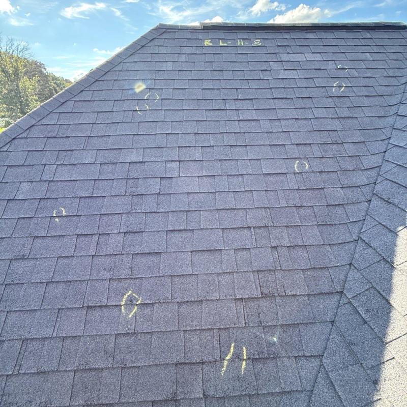 Asphalt shingles with hail damage marked for inspection