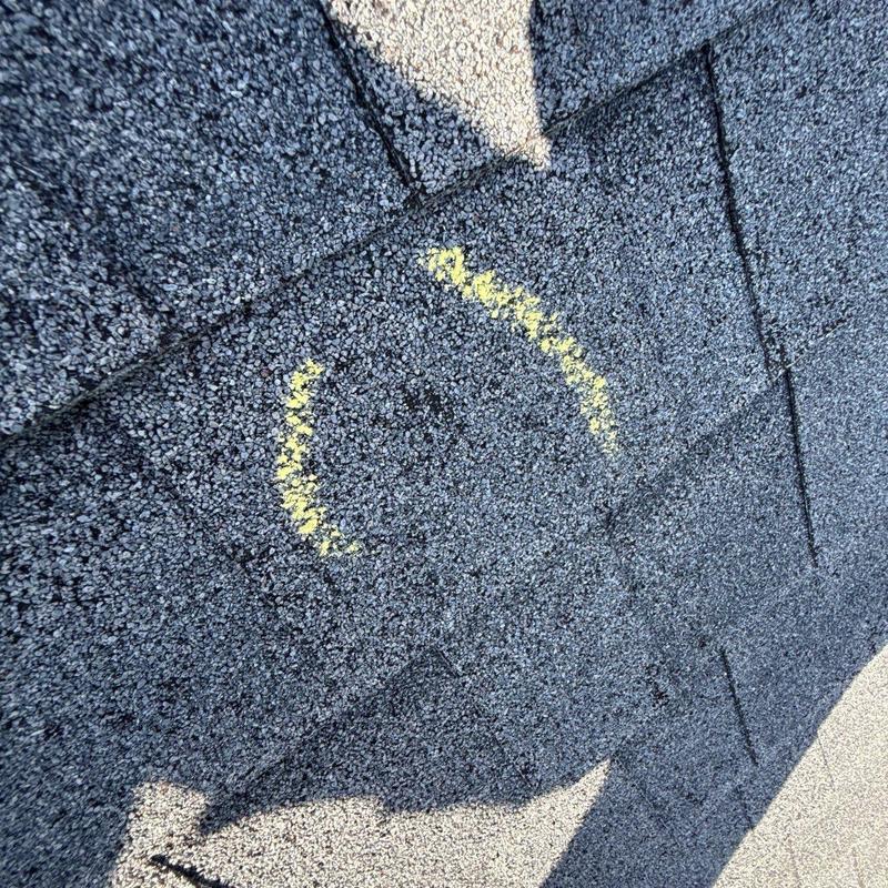 Hail-damaged asphalt shingle marked for inspection