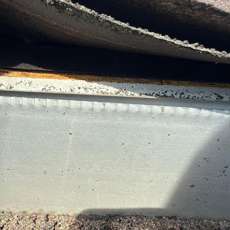 Roof edge metal flashing with rust damage and debris