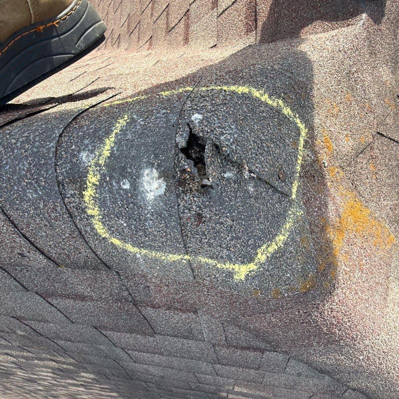 Roof shingle with hail damage marked for repair