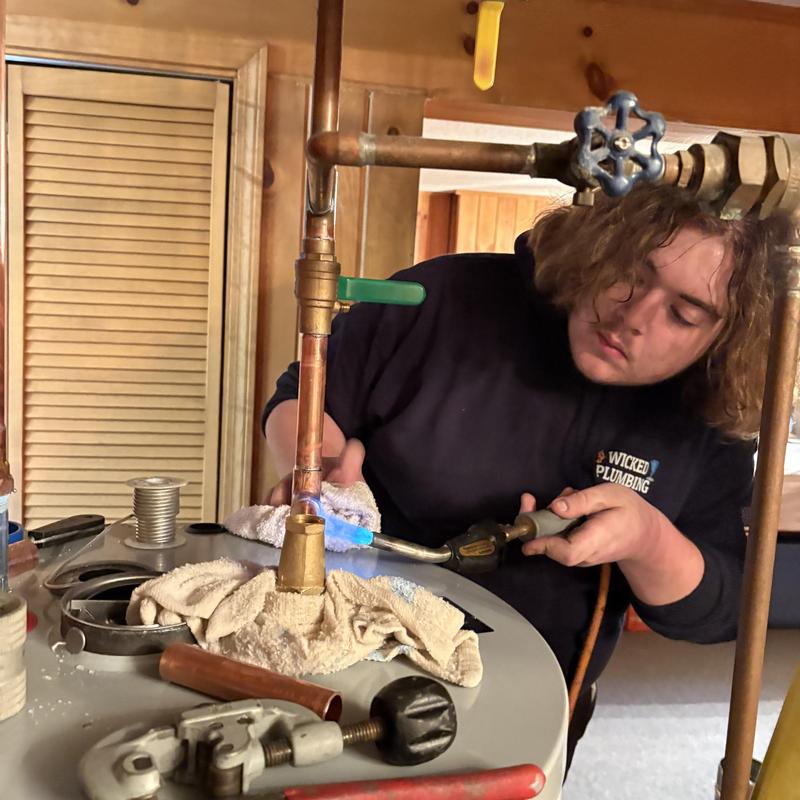 Water heater piping with plumber using torch