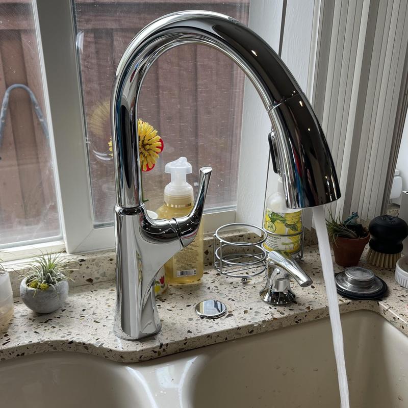 Kitchen faucet with running water on granite countertop