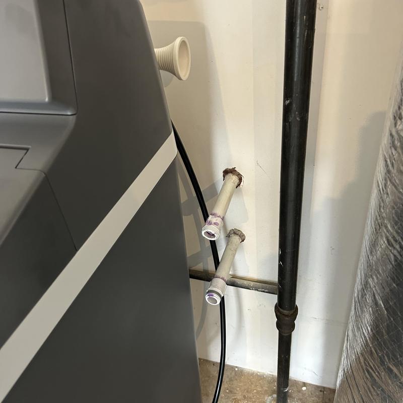Water softener hookup pipes near black drainpipe