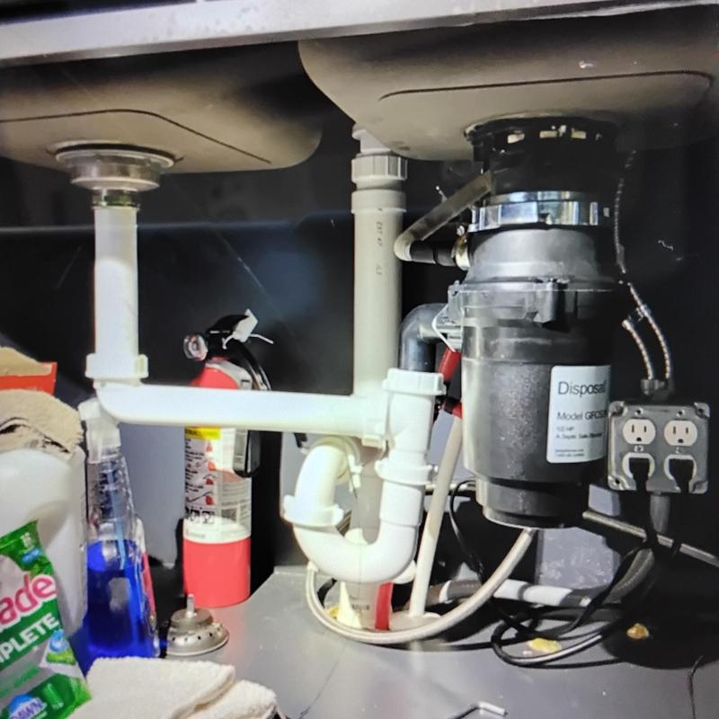 Garbage disposal and sink drain plumbing under kitchen sink