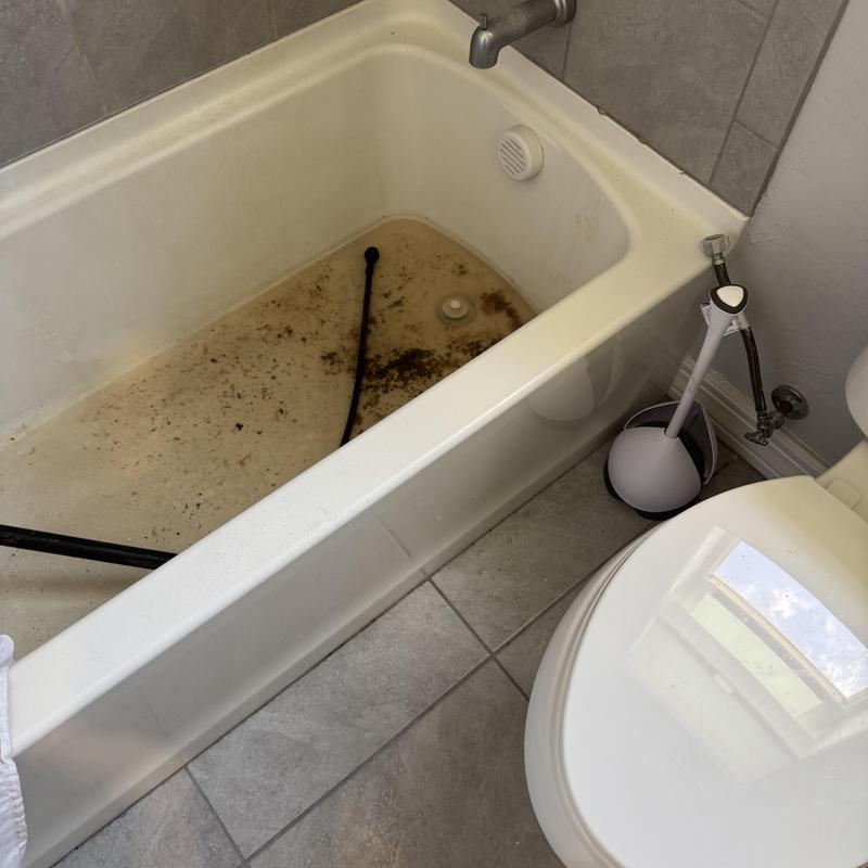 Bathtub drain clog with plumbing snake in bathroom