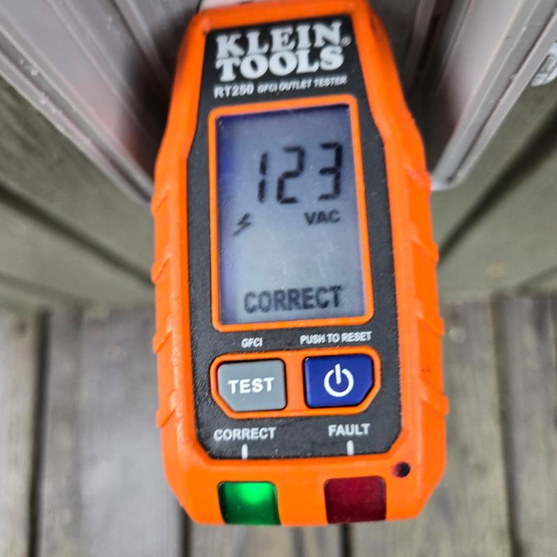 Electrical outlet voltage tester showing 123 VAC reading