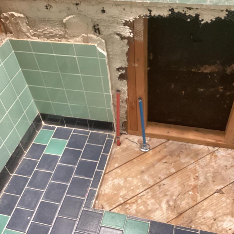 Bathroom water supply lines with exposed framing and tile floor