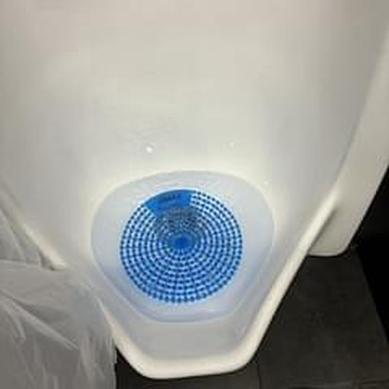 Commercial urinal with blue deodorizer block in place