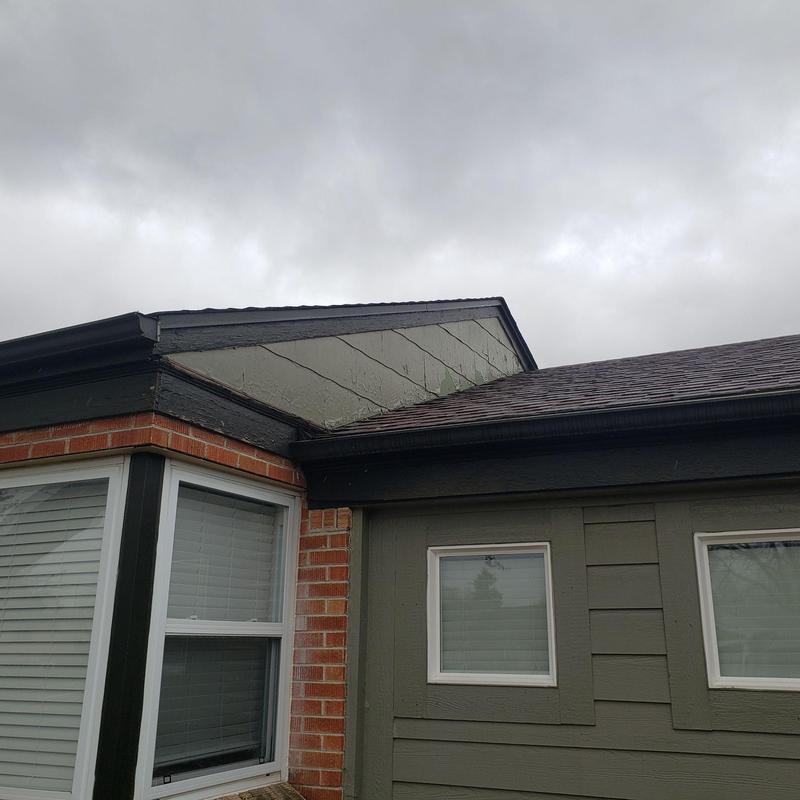 Shingle roof and siding with hail damage under cloudy sky
