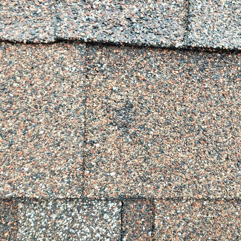 Asphalt roof shingles with hail impact damage close-up