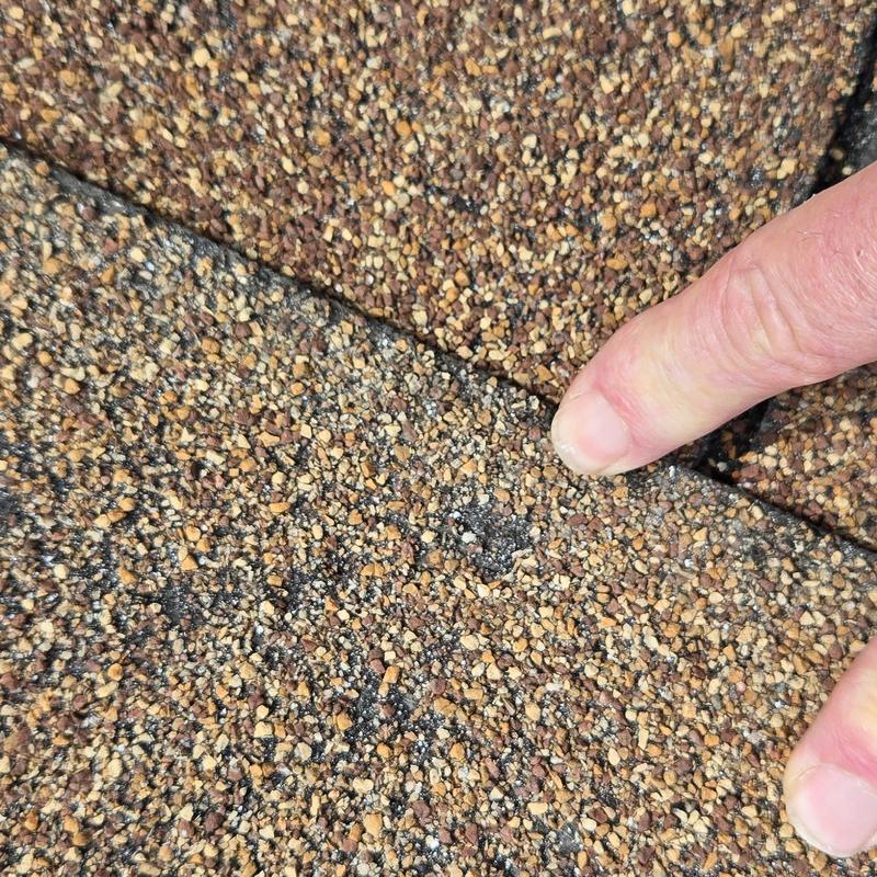 Roof shingles with hail damage close-up and finger pointing