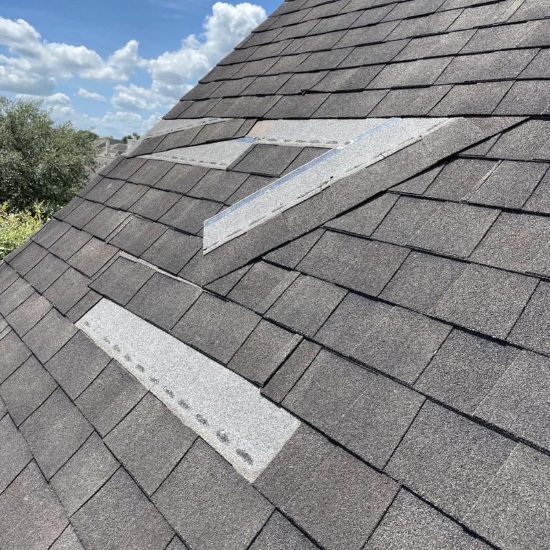 Damaged roofing shingles with patch repairs and nail pops