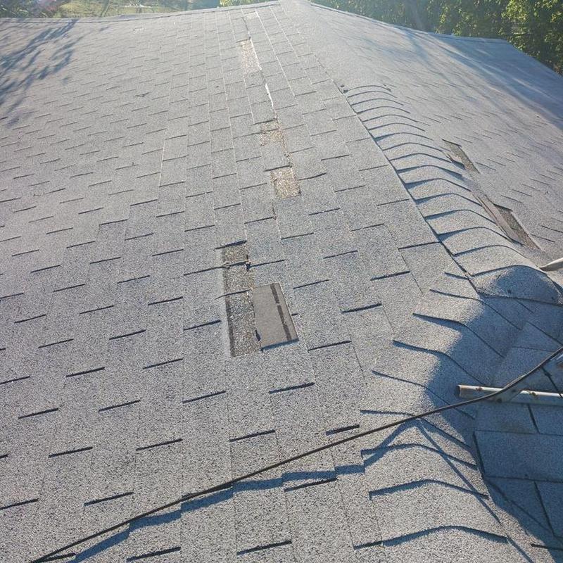 Asphalt shingle roof with wind damage and lifted shingles