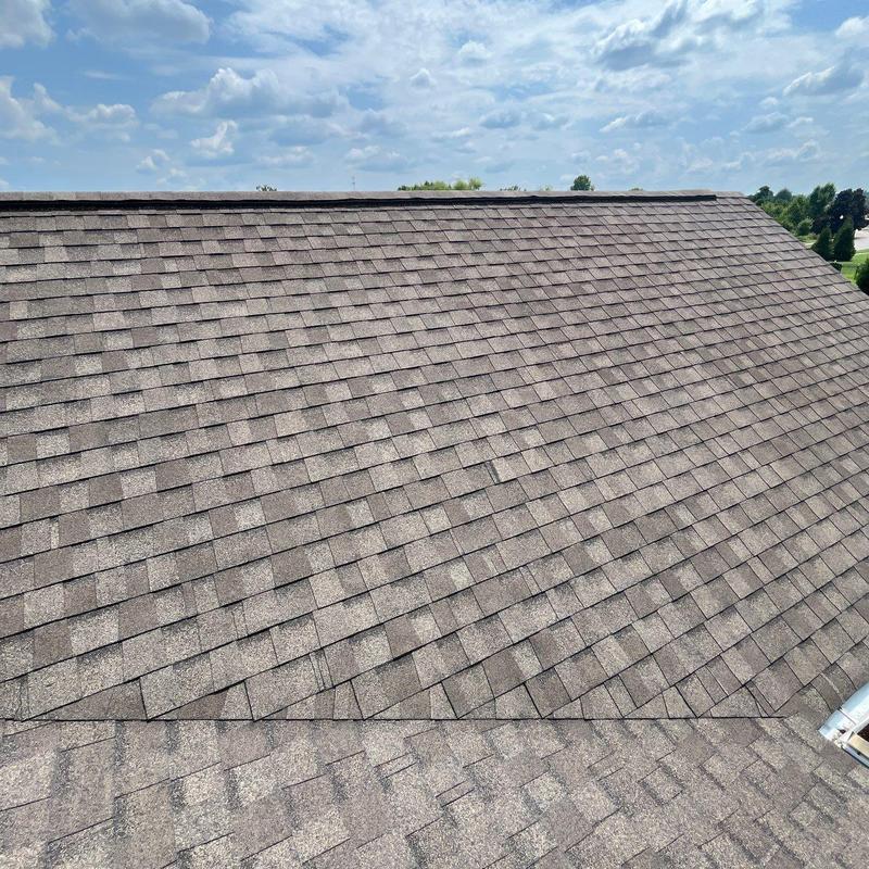 Asphalt shingle roof with hail damage inspection under clear sky