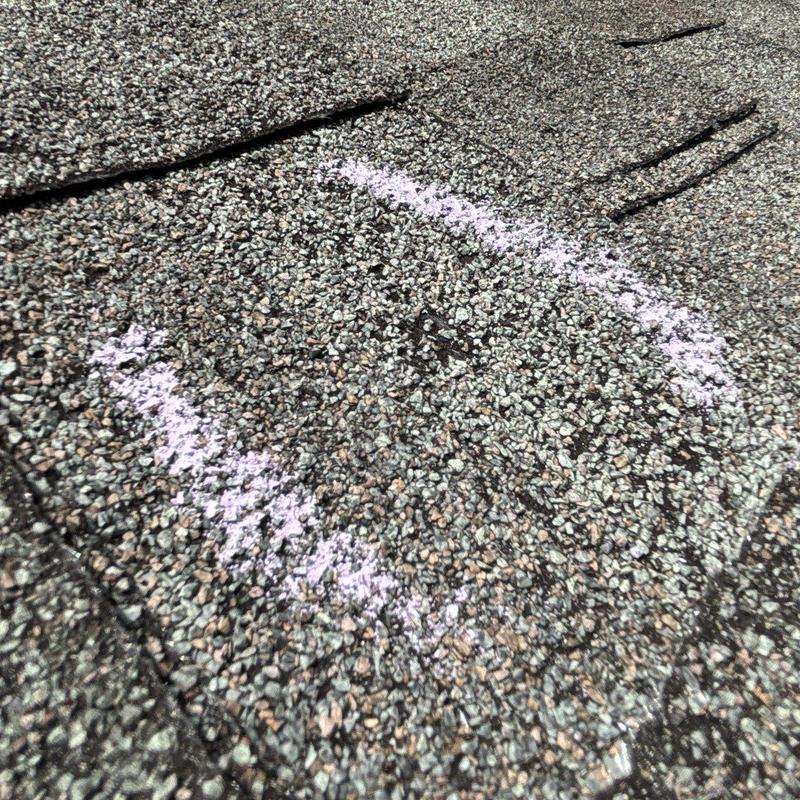 Asphalt shingles marked for hail damage on roof surface