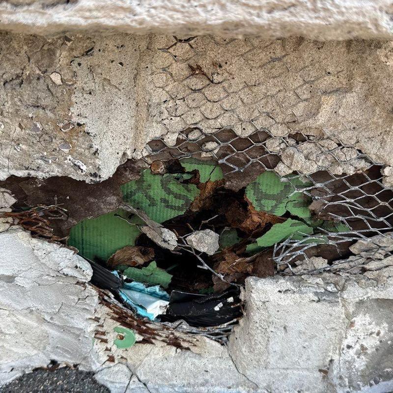 Concrete curb with exposed rebar and rust damage
