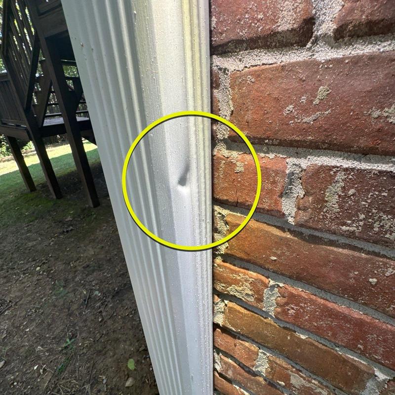 Vinyl siding dent damage next to brick wall