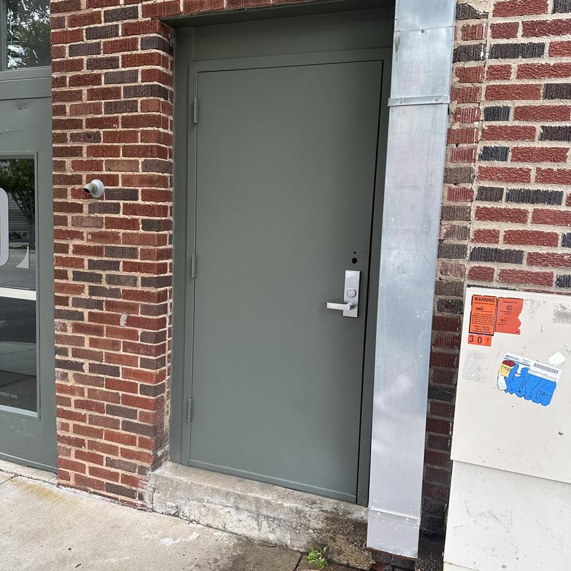 Exit device lever trim on metal door in brick wall