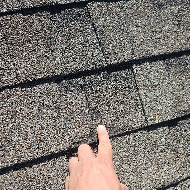 Shingle roof hail damage with finger pointing