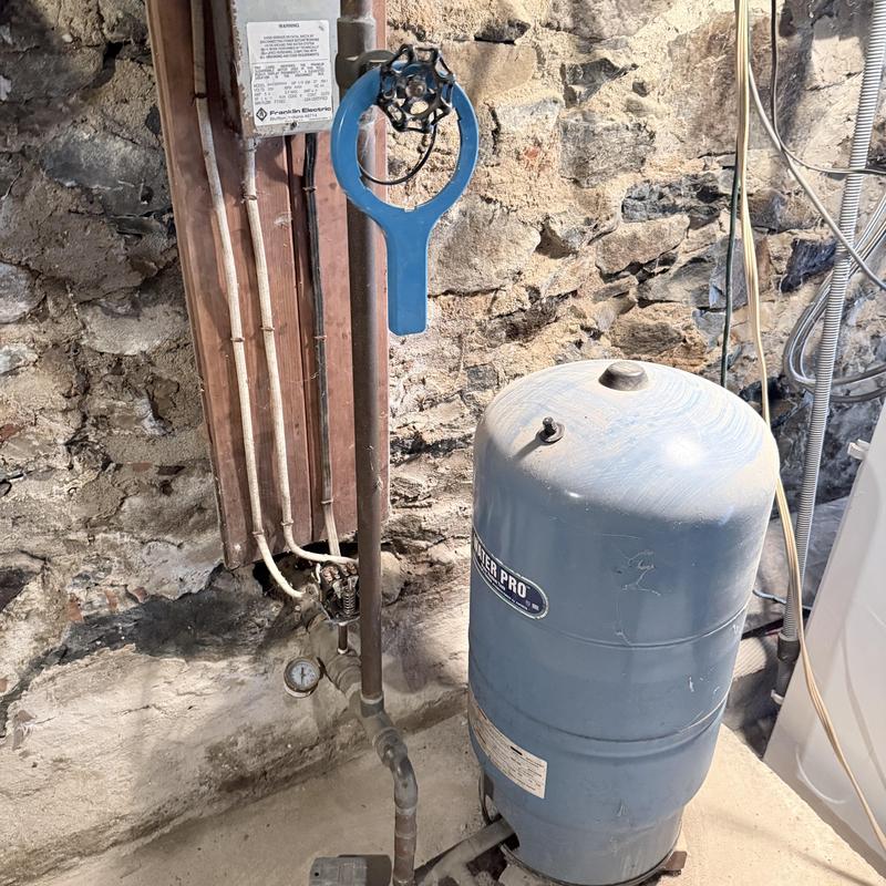 Well tank and valve assembly in basement plumbing system