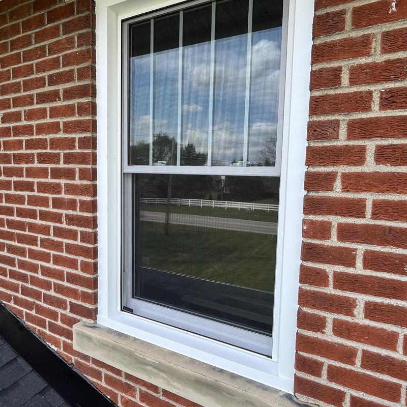 Double-hung window with white frame in brick wall