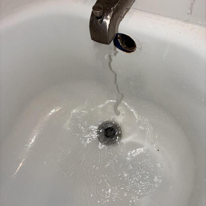 Bathroom sink drain flowing water after cleaning service