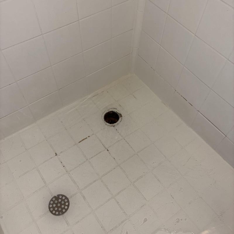 Shower drain with removed drain cover and clogged opening