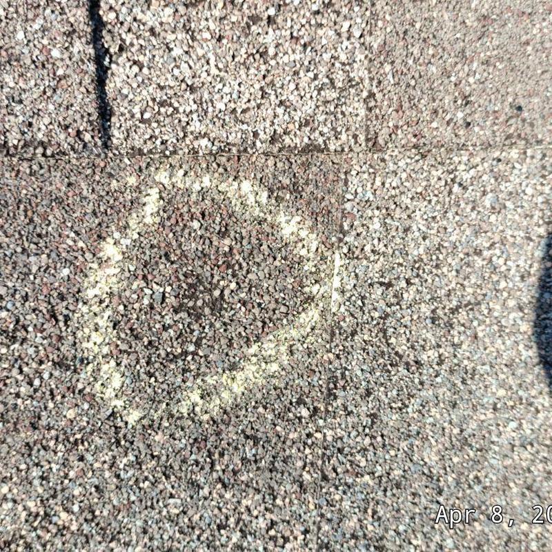 Asphalt shingle with chalk-marked damage spot