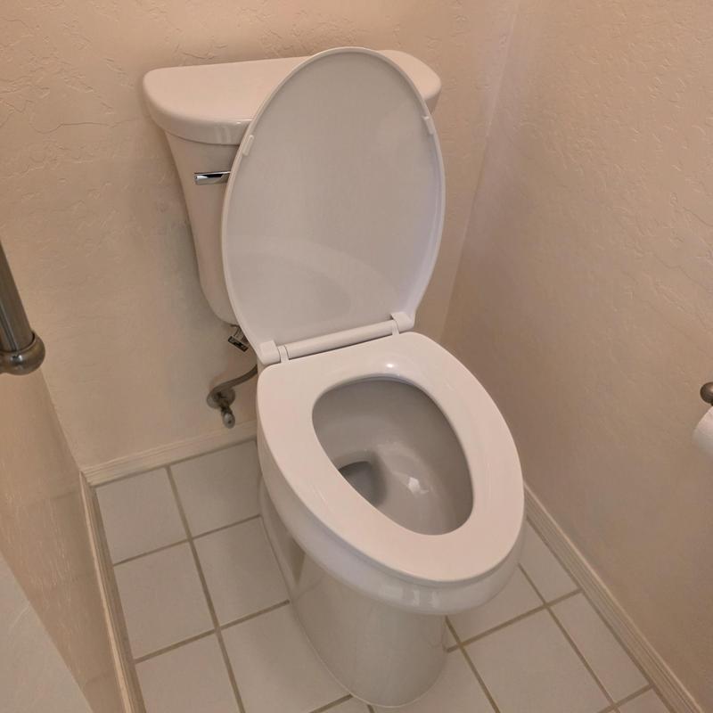 Toilet with open lid in small bathroom corner