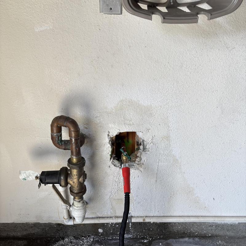Hose bib with attached water hose in wall outlet