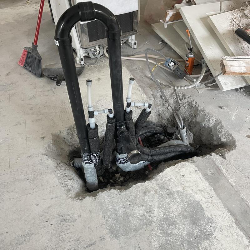 Kitchen sink plumbing pipes installed in concrete floor hole