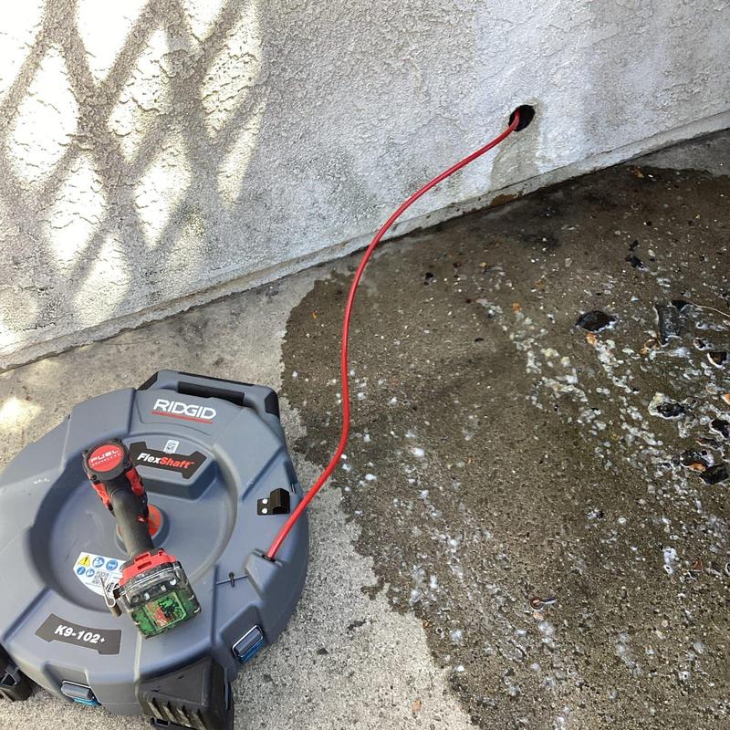 Drain clean-out with plumbing snake clearing blockage