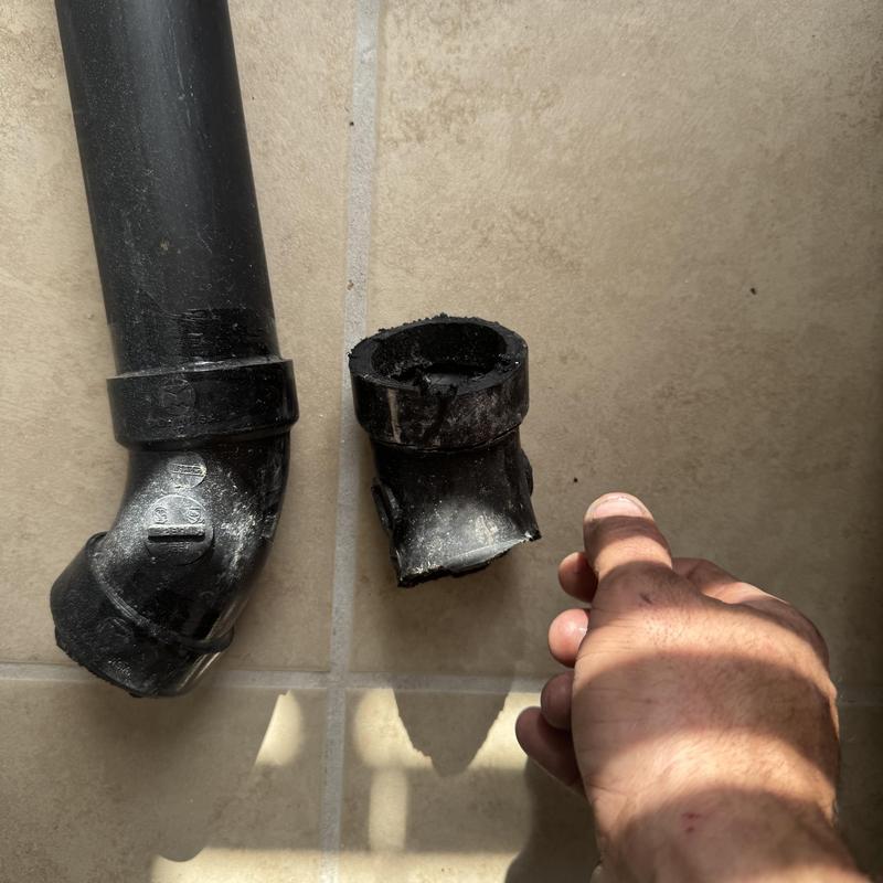 Kitchen sewer pipe broken fitting on tile floor