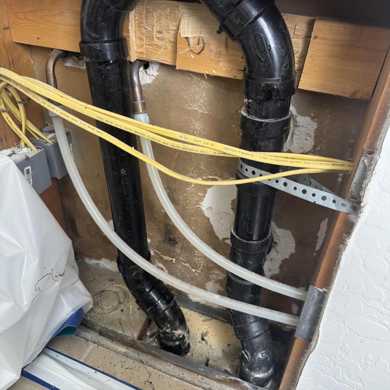 Black PVC sewer drain pipes behind drywall in kitchen area