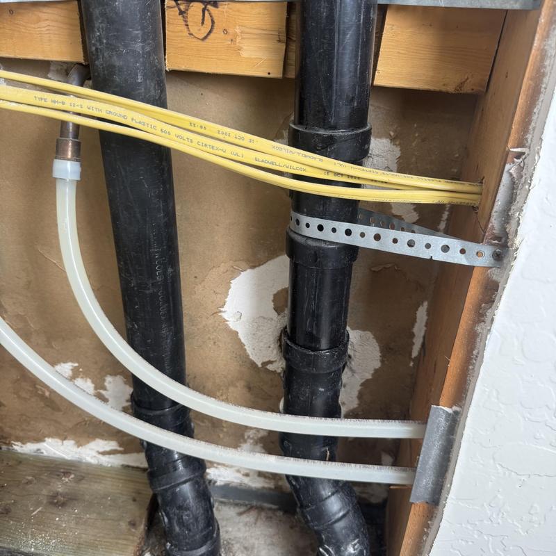 Sewer drain pipes behind drywall with electrical wiring