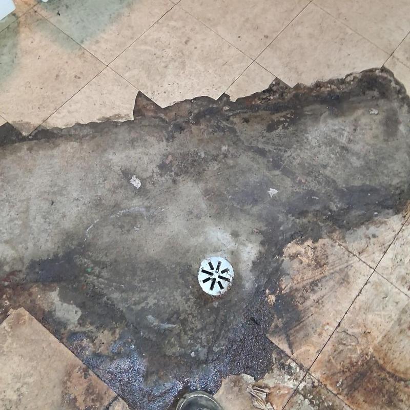Floor drain with surrounding damaged tile and concrete