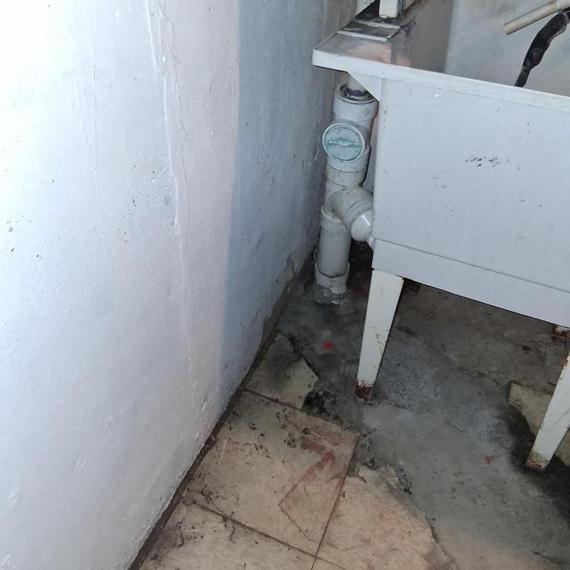 Drain pipe near laundry sink in basement corner