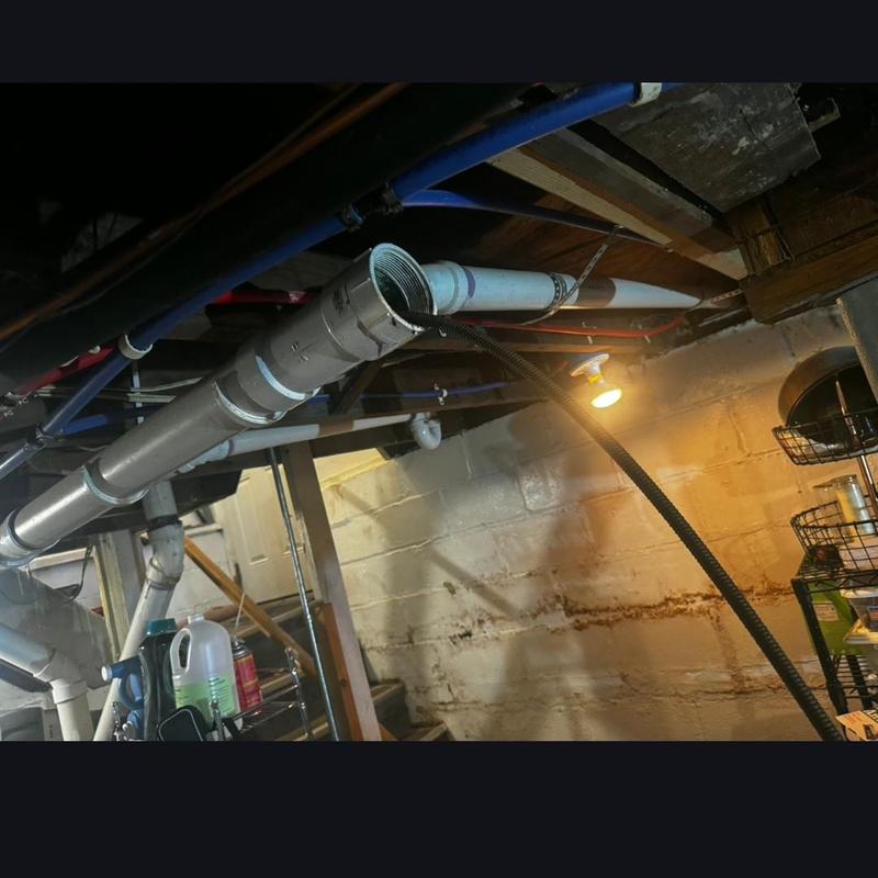 PVC cleanout pipe with plumbing snake in basement drain