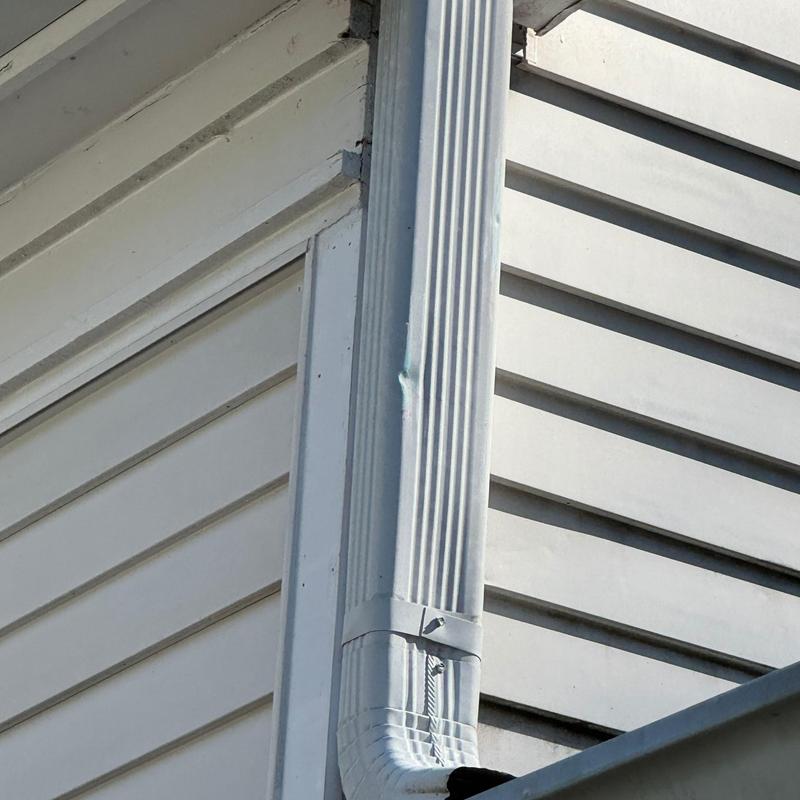 Aluminum downspout with dent and siding corner trim