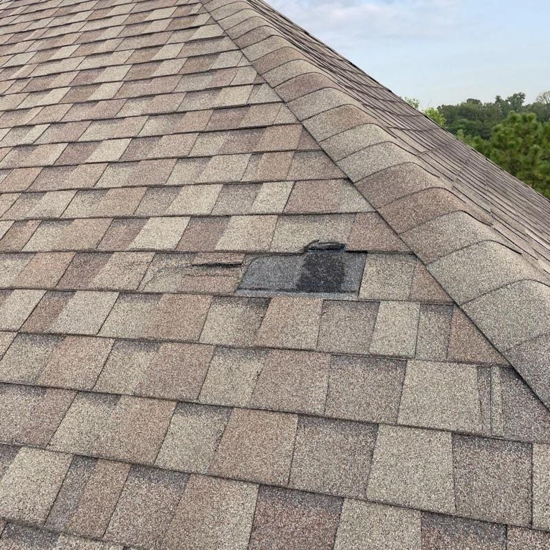 Architectural roof shingles with damaged patch near ridge