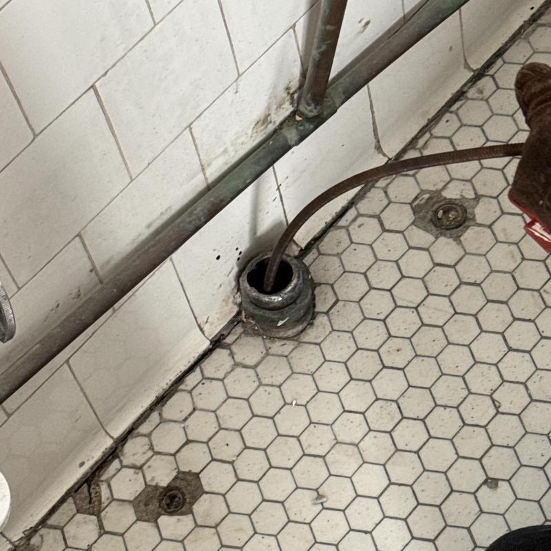 Sink drain cleaning with snake tool in old hex tile floor Sink drain cleaning with snake tool in old hex tile floor