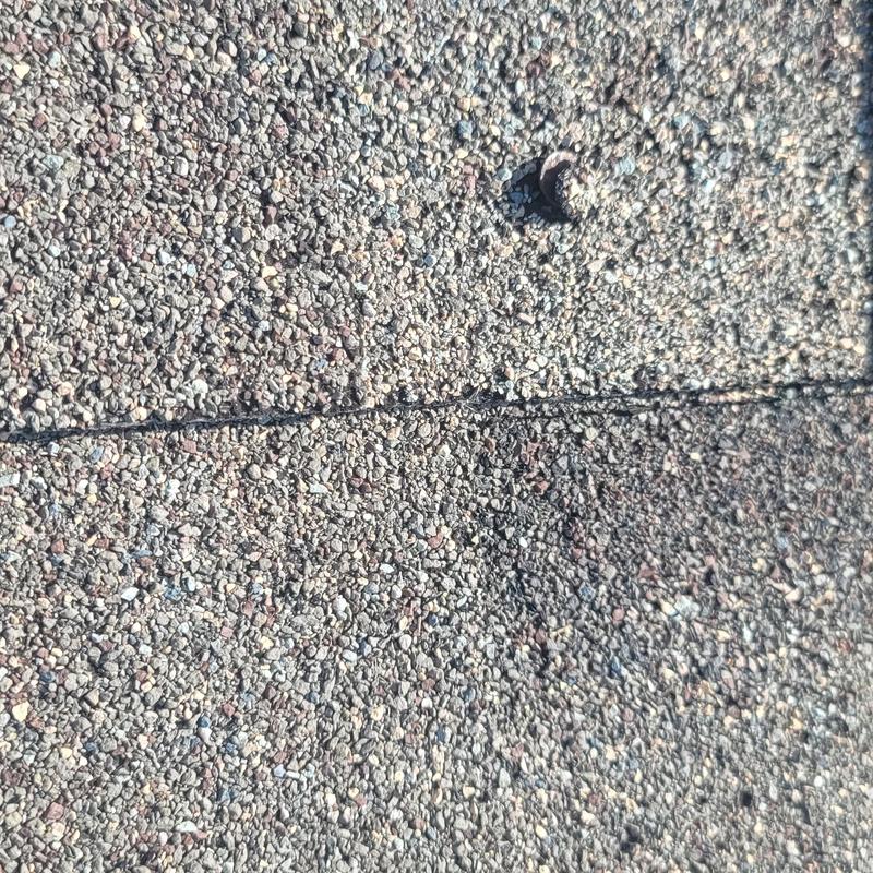 Asphalt shingle roof with hail damage marks and nail head